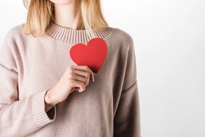 Kurkuma fördert die Herzgesundheit, als Symbole hält die Frau ein rotes Papierherz über die Brust